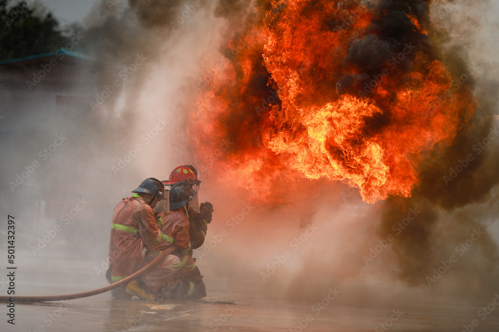 Obraz premium firefighter training firemen practice fighting the fire.fireman using water and extinguisher to fighting with fire flame in an emergency,fireman team fire drills.