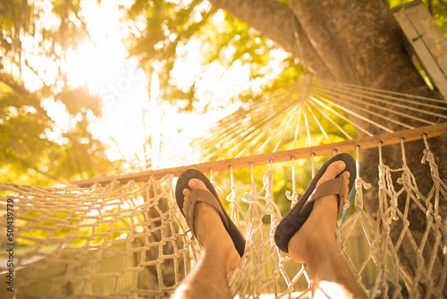 Person sitting back in hammock relaxing on a warm summer day 