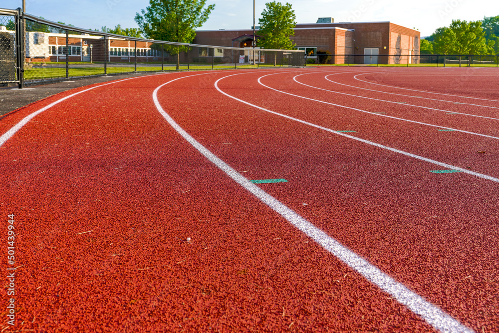 late afternoon photo of last turn on a new running track from a low perspective.	