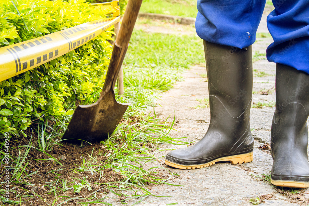 persona trabajadora en jardín con pala y botas limpiando para sembrar ...