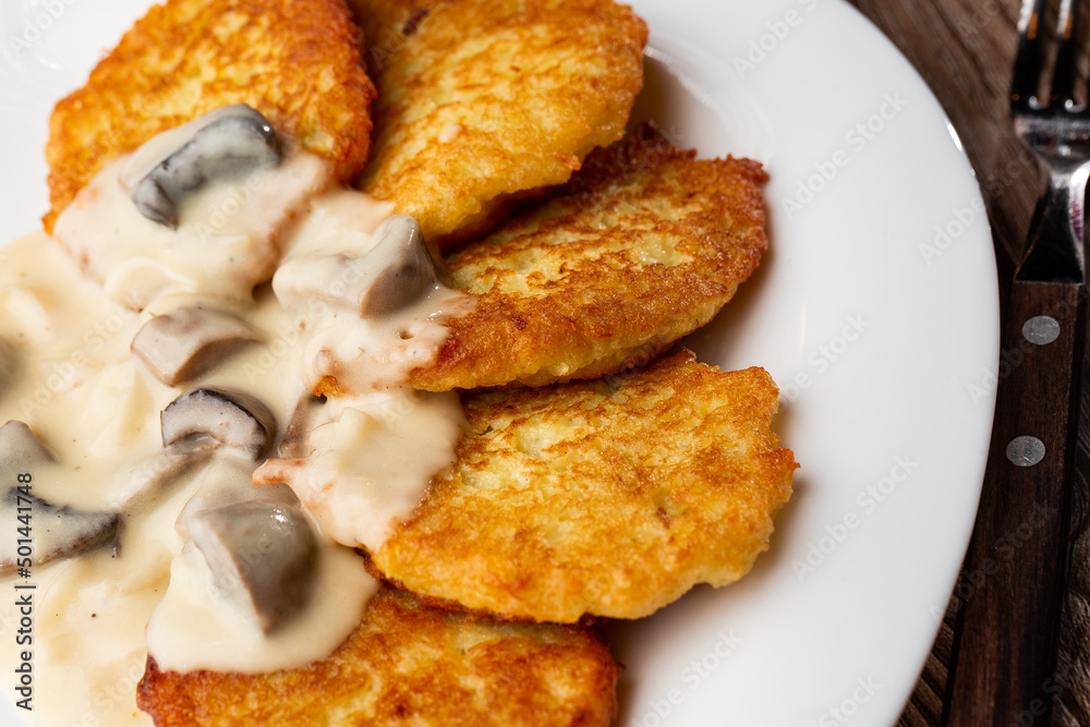 Pancakes with fried mushrooms and onions. Potato pancakes with mushrooms and sour cream. Ukrainian cuisine, European cuisine Pancakes with fried mushrooms and onions. Potato pancakes with mushrooms and sour cream. Ukrainian cuisine, European cuisine