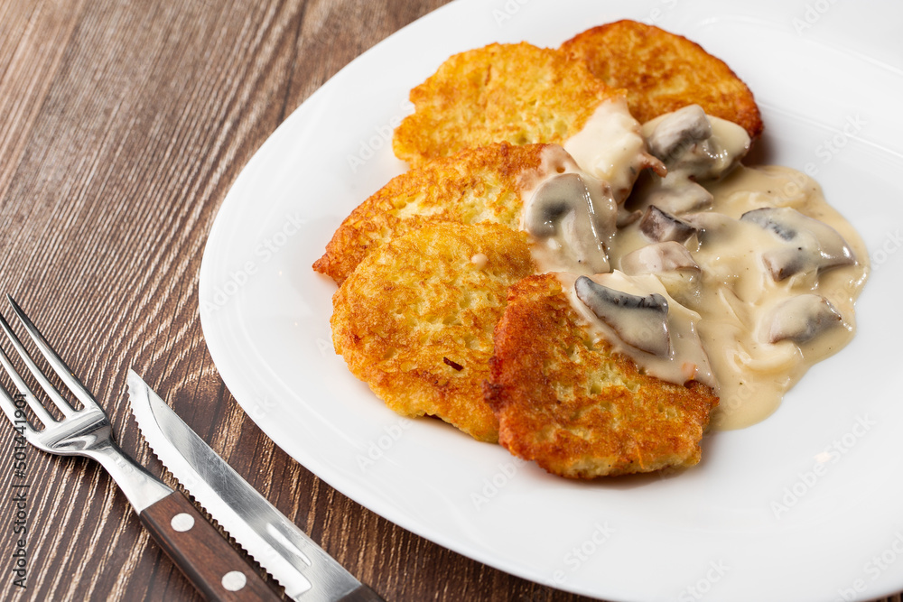 Pancakes with fried mushrooms and onions. Potato pancakes with mushrooms and sour cream. Ukrainian cuisine, European cuisine