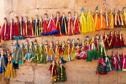 Traditional King and queen, called Raja Rani, handmade puppets or Katputli Sets are hanging from wall inside Jaislamer fort, Rajasthan, India. Dolls in Jaisalmer are popular and are sold to tourists. © mitrarudra