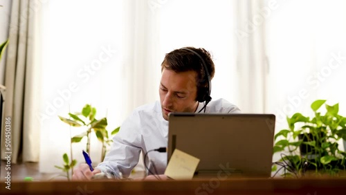Focused businessman in necktie suit making conference video call on laptop. Male professional call center manager working remotely taking note