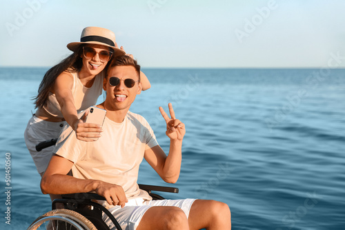 Happy man with physical disability and his girlfriend taking selfie at sea resort © Pixel-Shot