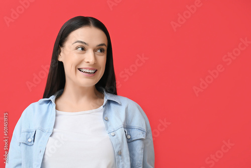 Beautiful woman with dental braces on red background