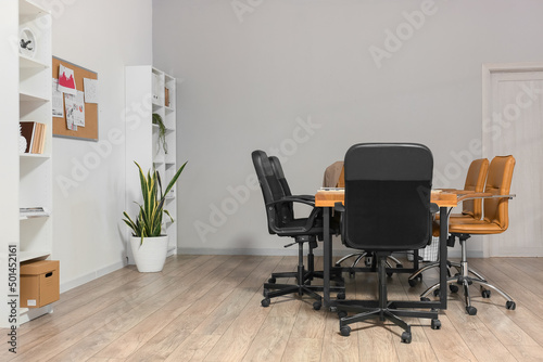 Interior of conference hall with table, chairs and shelf units