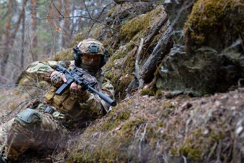 Modern warfare concept - a mercenary soldier in ambush in forest.