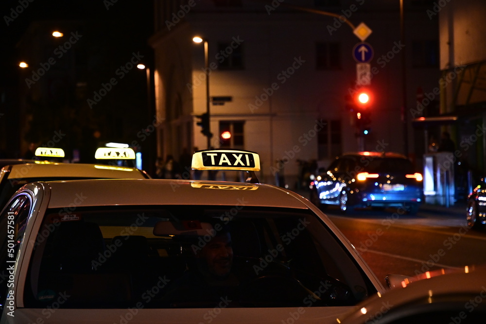 Drei Taxen stehen am Taxi-Stand, beleuchtetes Taxilogo in der Nacht, Taxischild in Frankfurt, Hessen, Deutschland