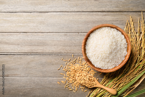 Flat lay of White rice with paddy rice ears on wood background.