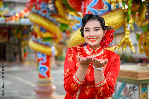 Asian beautiful woman wearing a cheongsam poses at shrine on Chinese New Year