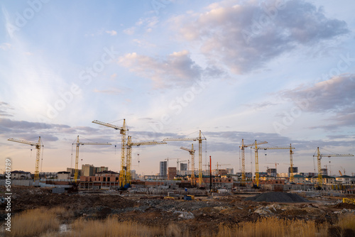 Construction site with cranes and buildings on the outskirts of town.