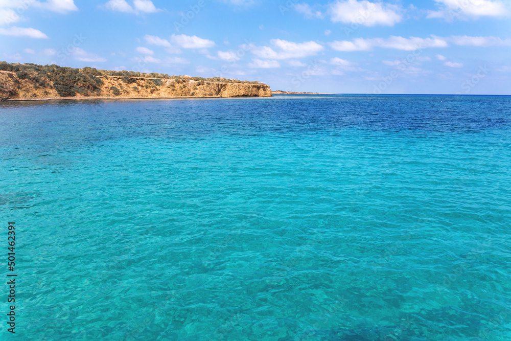 Fototapeta premium View of rocky coast turquoise sea waters on a sunny day with blue sky. Blue lagoon. Destination scenics seascape. Travel and adventure. Cyprus. Mediterrenian. No people