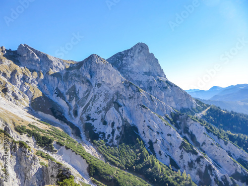 A close up view on a massive  stony mountains in Kaiserau Kreuzkogel region  Austrian Alps. The steep slopes are scarcely overgrown with grass. Sharp peaks. Dangerous mountaineering. Sunny summer day