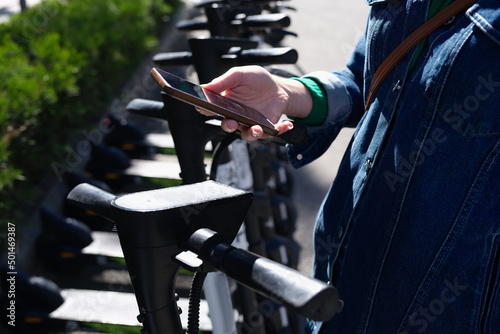 Φωτογραφία Woman paying rent of electric scooter using mobile app on street