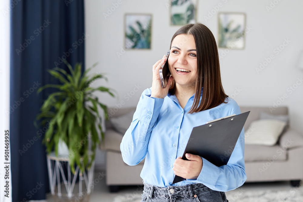 Smiling woman talking on the phone at home near the sofa. Feminine gossip on the smartphone.