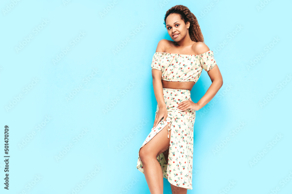 Beautiful black woman with afro curls hairstyle. Smiling model dressed in summer dress. Sexy carefree female posing near blue wall in studio. Tanned and cheerful Beautiful black woman with afro curls hairstyle. Smiling model dressed in summer dress. Sexy carefree female posing near blue wall in studio. Tanned and cheerful