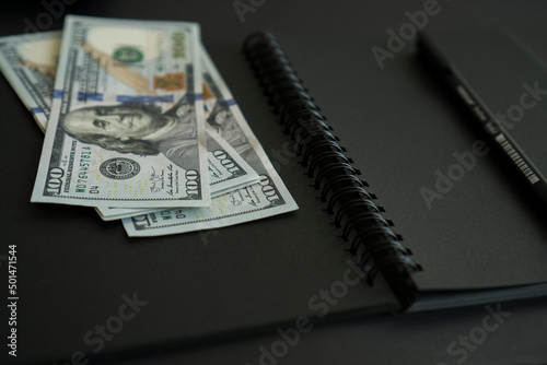 Dollars are on a black notebook.