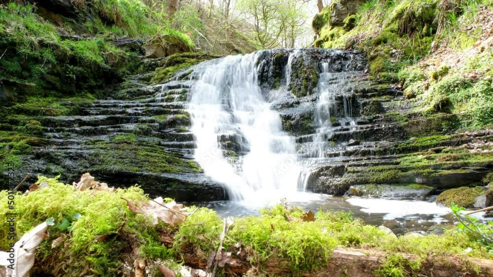 Waterfall in forest in the UK slider shot. 4k time lapse of water running over rocks, moss and trees. Waterfall in forest in the UK slider shot. 4k time lapse of water running over rocks, moss and trees.
