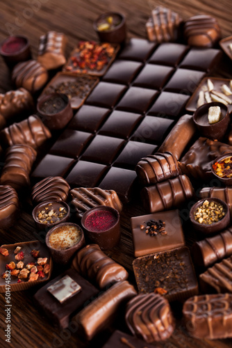 Chocolate bars and pralines on wooden background