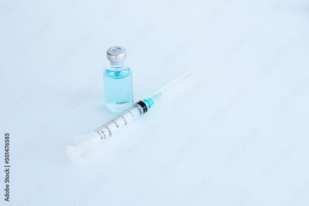 Vaccine bottle and syringe placed on a white table. Healthcare and medical concept. Vaccine bottle and syringe placed on a white table. Healthcare and medical concept.