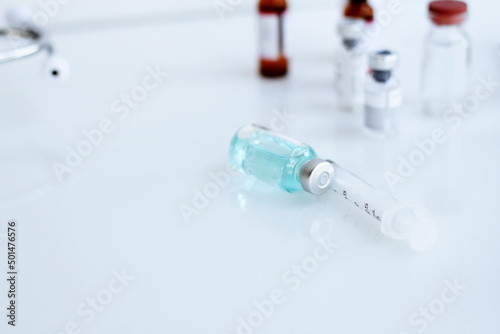 Vaccine bottle and syringe placed on a white table. Healthcare and medical concept.