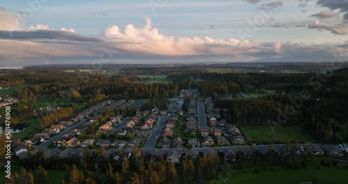 Wide establishing shot of an American developed neighborhood surrounded by forests and cloudy skies at sunset. photo