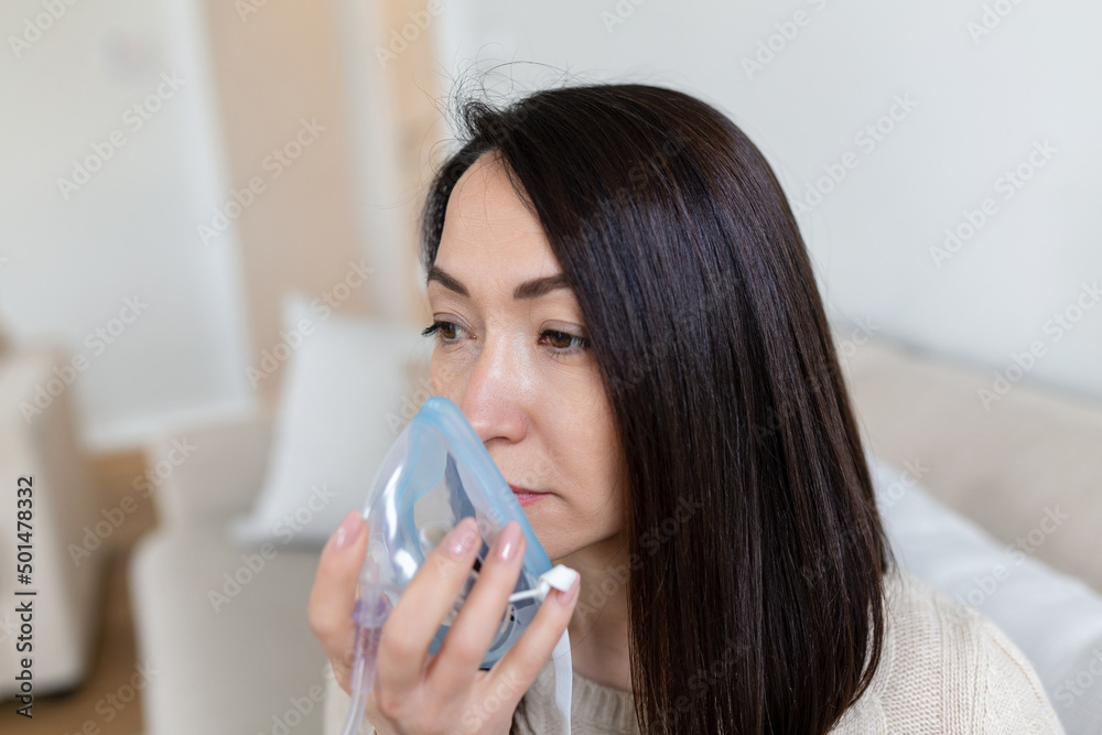Sick Asian woman making inhalation, medicine is the best medicine. Ill woman wearing an oxygen mask and undergoing treatment for covid-19. woman with an inhaler Sick Asian woman making inhalation, medicine is the best medicine. Ill woman wearing an oxygen mask and undergoing treatment for covid-19. woman with an inhaler