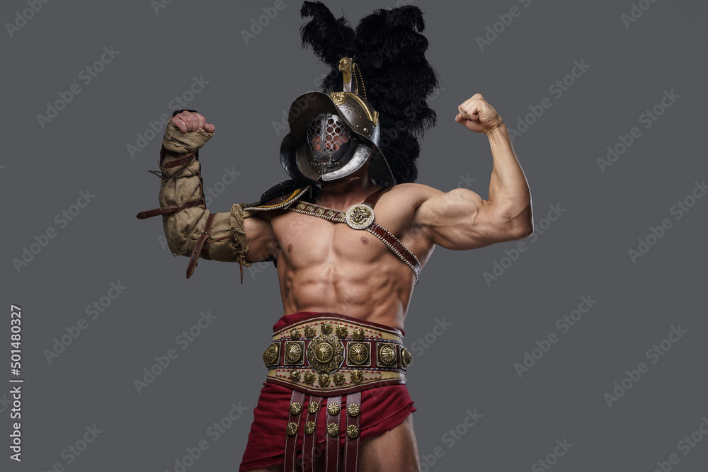 Portrait of colosseum warrior with plumed helmet showing his strength against grey background.