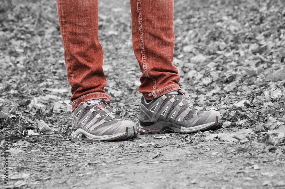 sneakers on the path. man stands with her foot in the woods. illustration of travel. grey shoes on a natural background. hiking concept