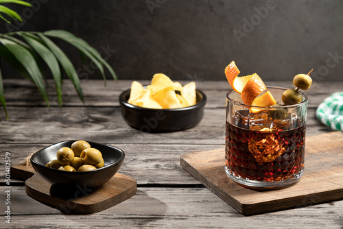 Photo Vermouth cocktail with snacks on wooden base on dark background