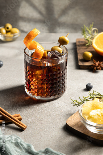 Vermouth cocktail with snacks and ingredients on concrete background. Vertical format. Typical Spanish appetizer.