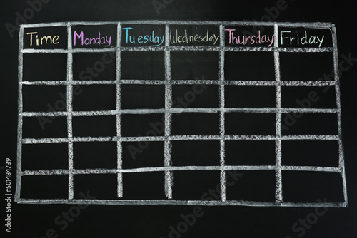 Weekly school timetable drawn on black chalkboard