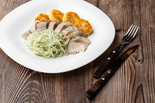 Herring with potatoes and onions on a plate. Ukrainian traditional cuisine on wooden background.