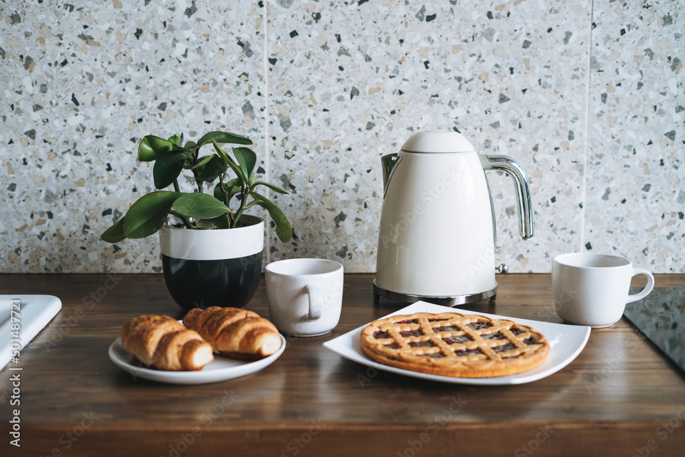 Work surface table with pastries and kettle in kitchen at home Work surface table with pastries and kettle in kitchen at home
