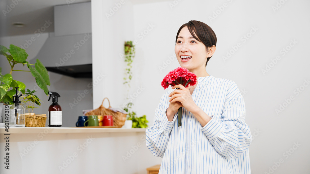 カーネーションを手にする若い女性 母の日のイメージ カーネーションを手にする若い女性 母の日のイメージ