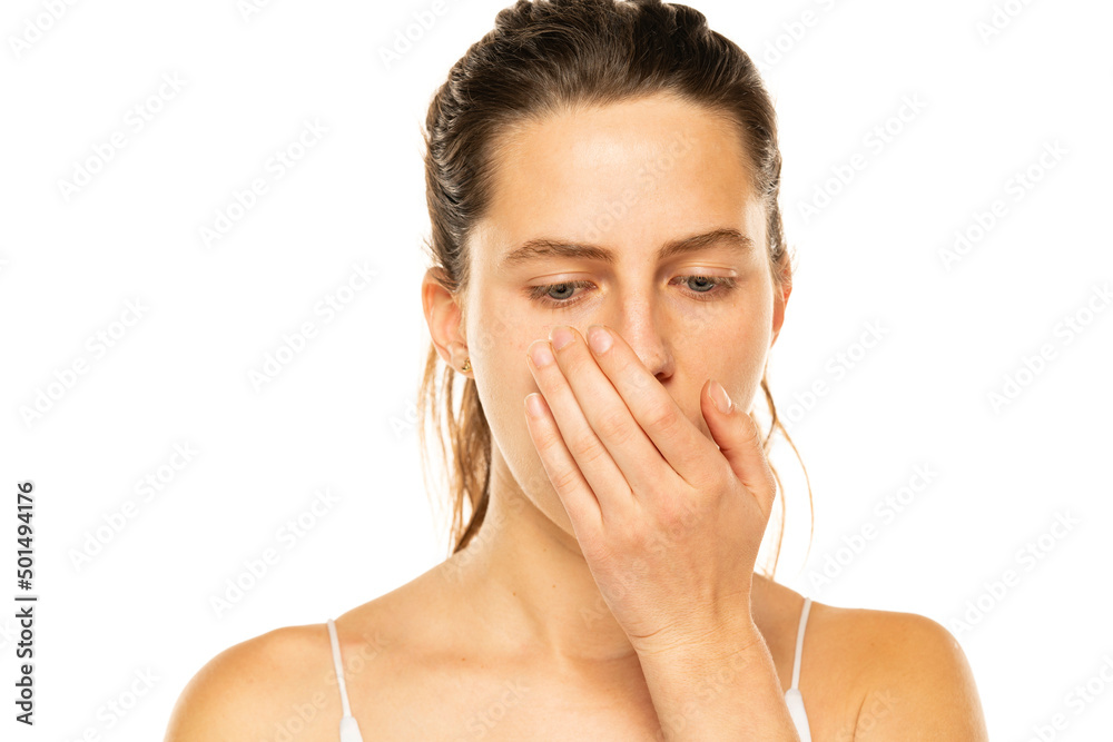 a young woman checks her breath with her palm on a white background a young woman checks her breath with her palm on a white background