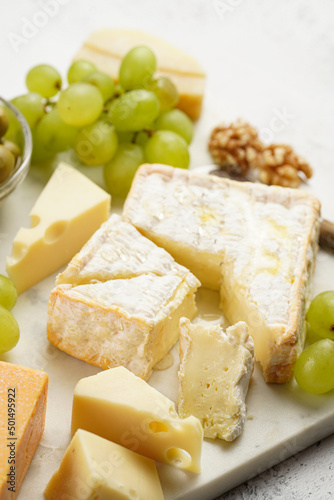 Cheese platter with organic cheeses - blue cheese cheddar, emmantaler, french soft cheese with strong smell, italian parmesan, grapes, tomatoes, olives, nuts and crackers on marble board
