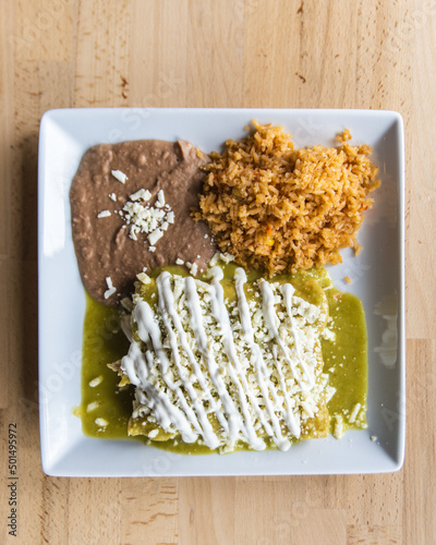 Vertical shot of a Mexican dish of enchiladas verdes with rice and beans photo