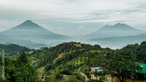 Green plants on hills and Volcan de Fuego mountains on the horizon in Antigua, Guatemala photo