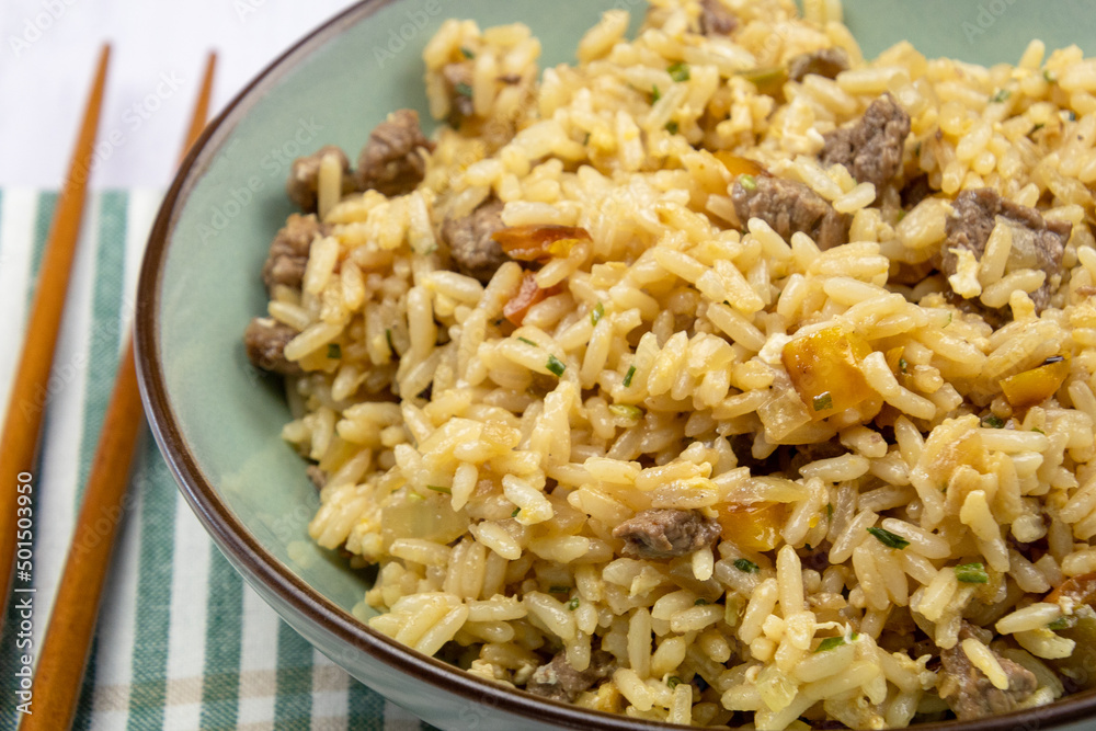 close up of a beef fried rice in a plate on a table close up of a beef fried rice in a plate on a table