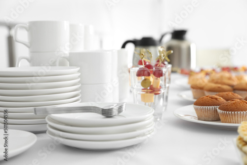 Table with different delicious snacks and dishware indoors. Coffee break