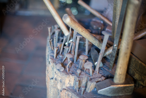 Closeup shot of old nails and hammers on a wood stump at the blacksmith shop photo