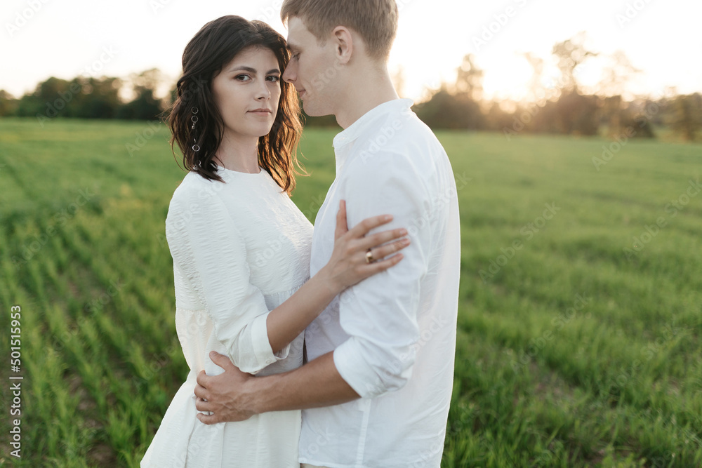 Portrait of a young romantic couple hugging each other in a field at sunset Portrait of a young romantic couple hugging each other in a field at sunset