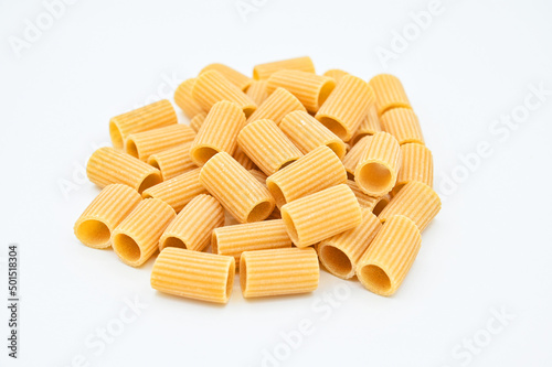 Closeup of raw rigatoni pasta in a white bowl on a white background photo