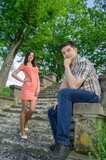 Young couple on stone steps in the park. Man and woman on a background of summer greenery.