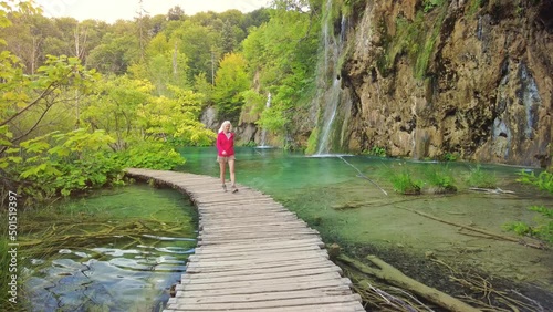 Woman walking on the Milino Jezero lake jetty under the Galovacki Buk waterfall of Plitvice Lakes National Park in Croatia in the Lika region. UNESCO World Heritage of Croatia named Plitvicka Jezera. photo