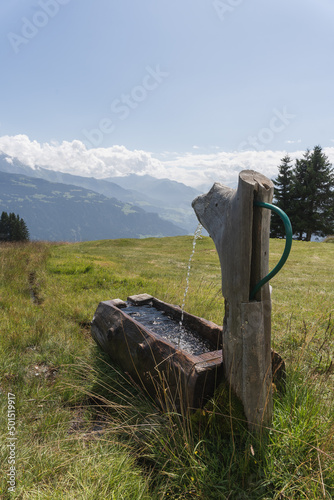 Vertical shot of a fount for drinking water in the field in Switzerland Falera Graubunden Grisons photo