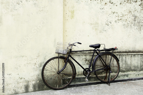 Black vintage bicycle nearle wall on cobblestone street.