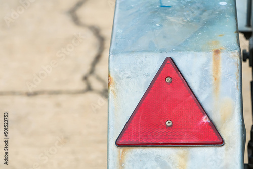 Red triangle shaped safety reflector on rusty metal surface photo